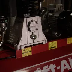Detaljerad bild av en kompressor, visar hur fungerar en kompressor med dess motor och tank.