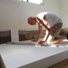 Man knäböjer och kontrollerar med vattenpass för att isolera med cellplast.