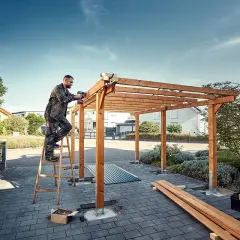 Man bygger carport med trästomme och skruvdragare.