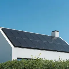 Modernt vitt hus med många mörka solceller på taket, som visar olika typer av solceller för hållbar energi.