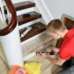 Man applicerar lim med en fogspruta på en trappsteg inomhus, redo för ny golvläggning.