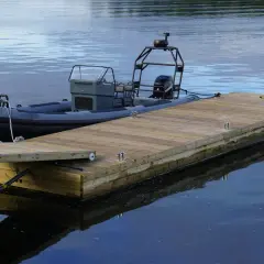 En grå RIB-båt ligger förtöjd vid en nybyggd flytbrygga. Perfekt för att bygga flytbrygga och njuta av vattnet.