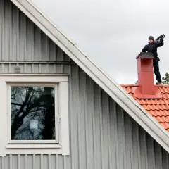 Sotare på taket till en villa. Regelbunden sotning är viktigt för säkerheten.