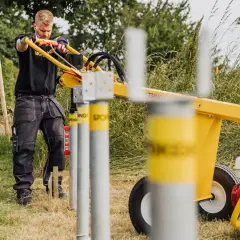 Man använder en markskruv-maskin från Biltema för att sätta stolpar i marken.