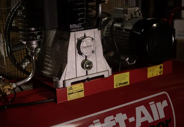 Detaljerad bild av en kompressor, visar hur fungerar en kompressor med dess motor och tank.
