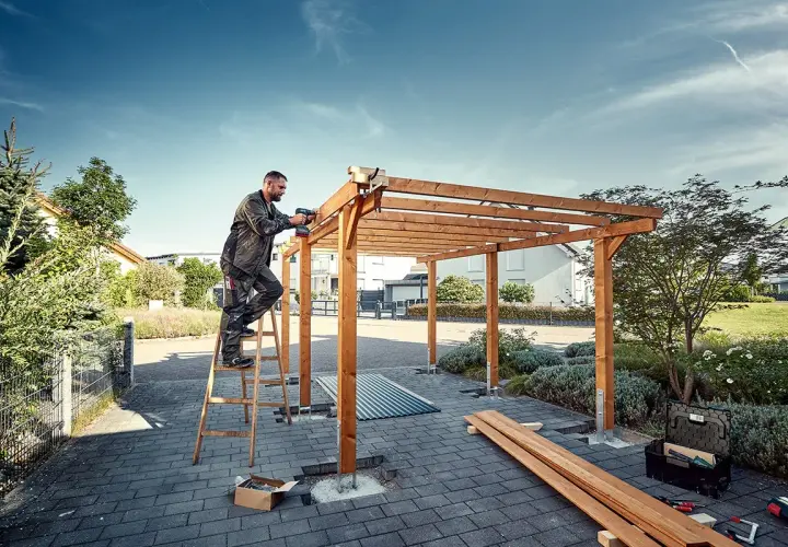 Man bygger carport med trästomme och skruvdragare.