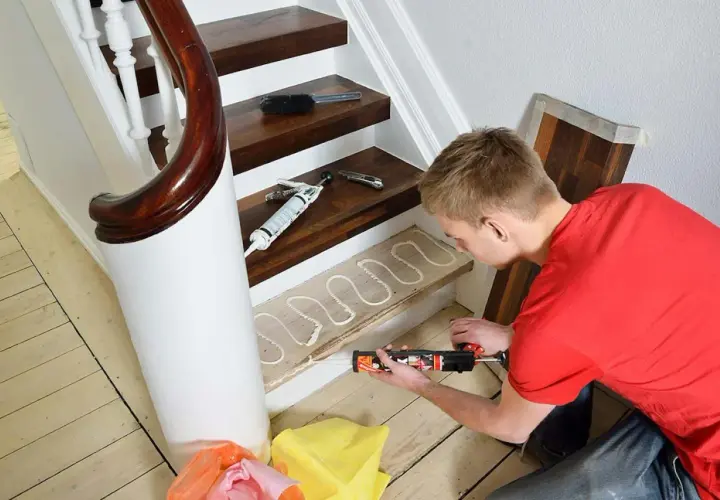 Man applicerar lim med en fogspruta på en trappsteg inomhus, redo för ny golvläggning.