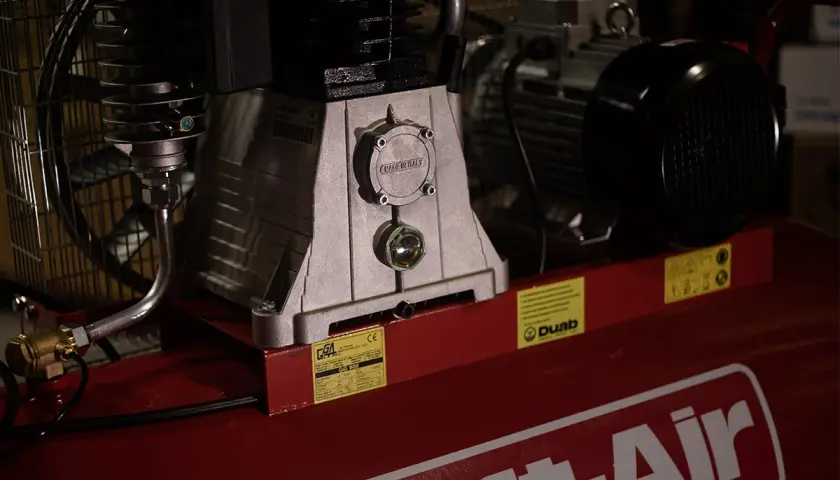 Detaljerad bild av en kompressor, visar hur fungerar en kompressor med dess motor och tank.