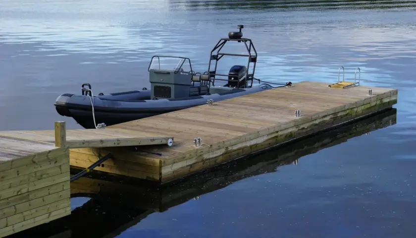 En grå RIB-båt ligger förtöjd vid en nybyggd flytbrygga. Perfekt för att bygga flytbrygga och njuta av vattnet.