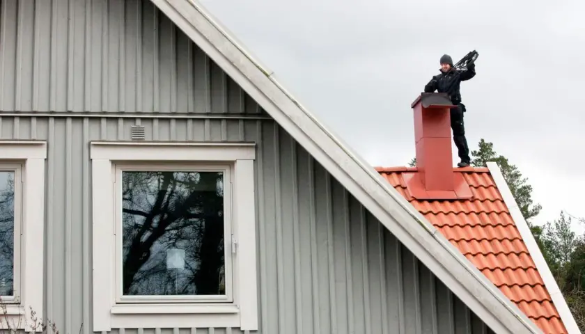 Sotare på taket till en villa. Regelbunden sotning är viktigt för säkerheten.