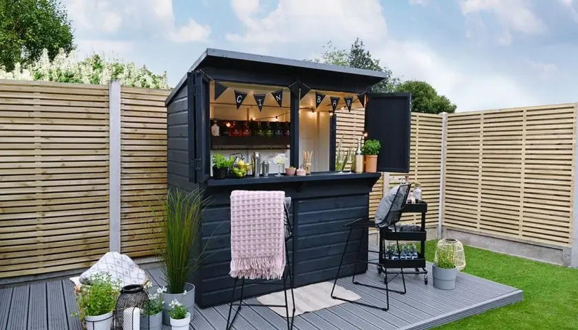 Svart utomhusbar med "GIN BAR"-girlang, redo för gäster. Perfekt för att bygga bar i trädgården.