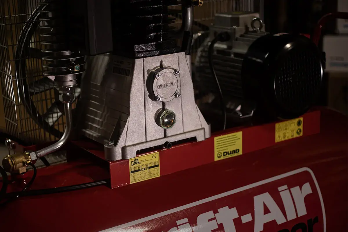 Detaljerad bild av en kompressor, visar hur fungerar en kompressor med dess motor och tank.