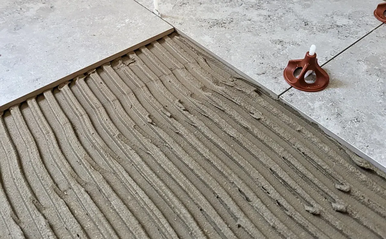 Klinker på klinker läggs med fix. En plattsättare arbetar med att jämna ut fixet för ett perfekt resultat.