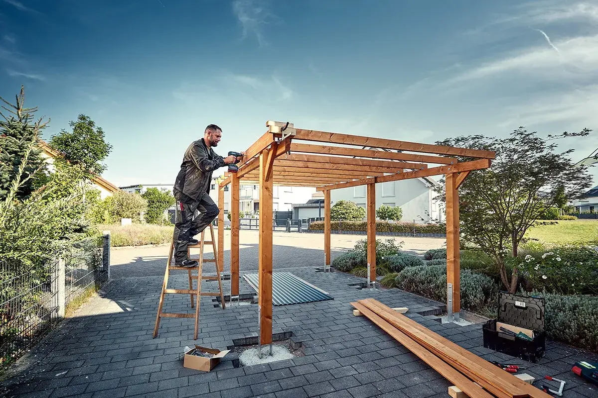 Man bygger carport med trästomme och skruvdragare.
