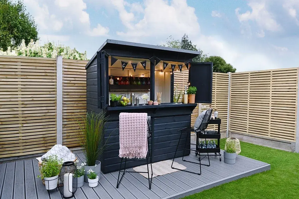 Svart utomhusbar med "GIN BAR"-girlang, redo för gäster. Perfekt för att bygga bar i trädgården.