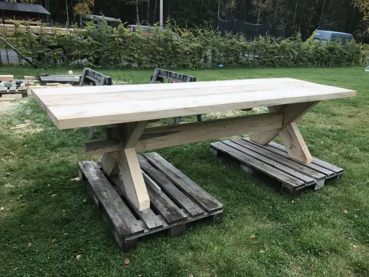 Ett stadigt, nybyggt utebord av tr&auml; st&aring;r p&aring; pallar i gr&auml;set. Perfekt f&ouml;r att bygga utebord och njuta av sommaren.
