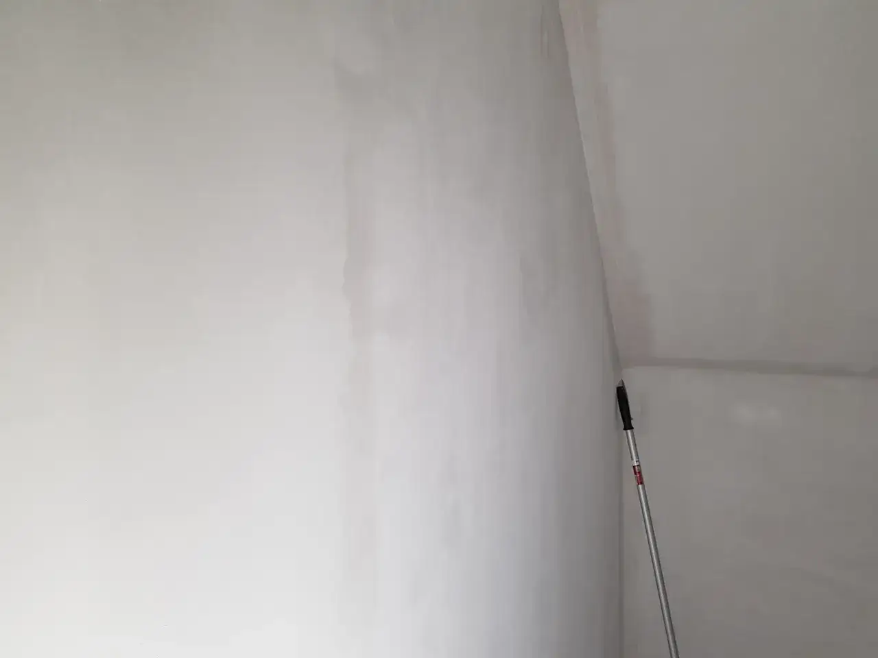 En v&auml;gg med spackel som torkar. En l&aring;ng skrapa st&aring;r lutad i h&ouml;rnet.
