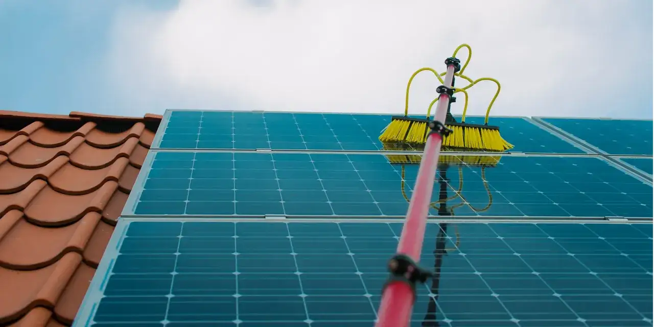 Borste reng&ouml;r solceller p&aring; ett tak. Regelbundet solceller underh&aring;ll s&auml;kerst&auml;ller maximal effektivitet.