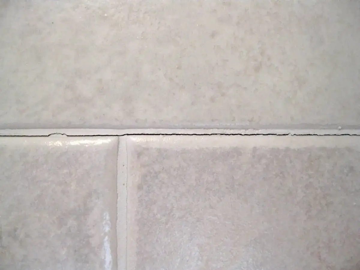 Detaljbild av kakel med en misslyckad fogning. Fogen har spruckit och ser oj&auml;mn ut.