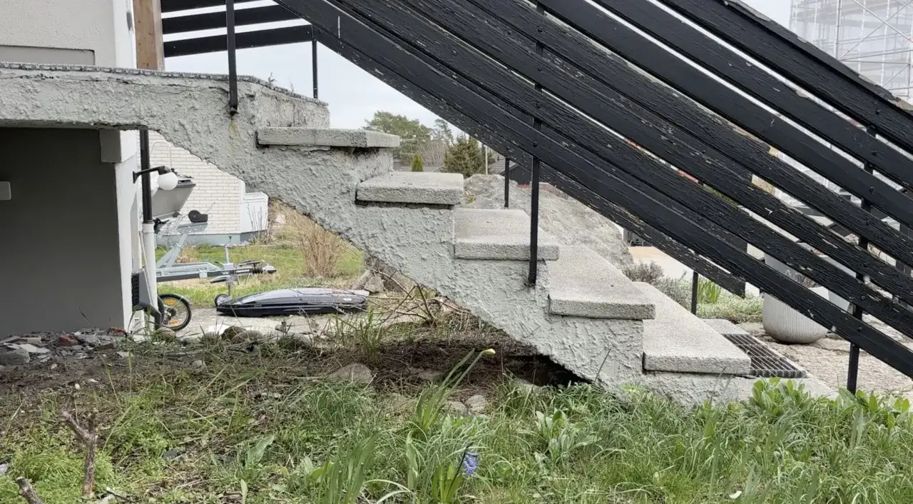 En betongtrappa med svarta r&auml;cken, redo f&ouml;r gjuta trappa. En trailer och takbox syns i bakgrunden.
