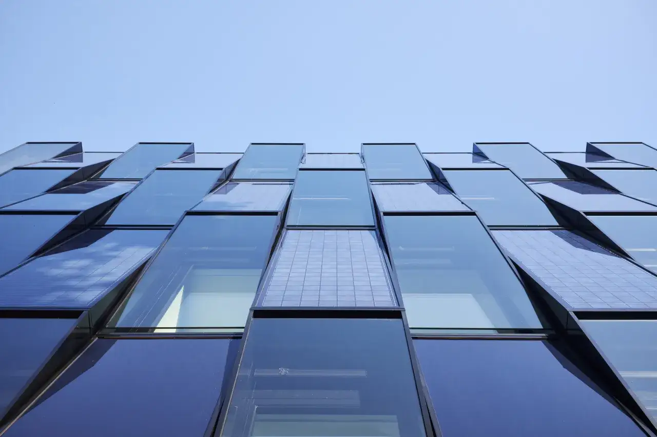 Modern byggnad med en fasad av glas och solceller som f&aring;ngar solljuset.