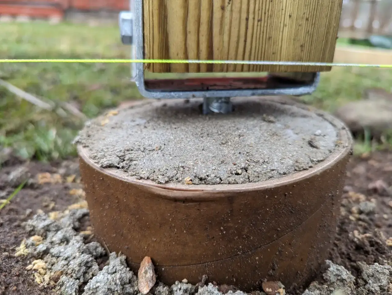 En nybyggd stolpe f&ouml;r ett staket vilar p&aring; en betongplint. En sn&ouml;rning visar h&ouml;jden.